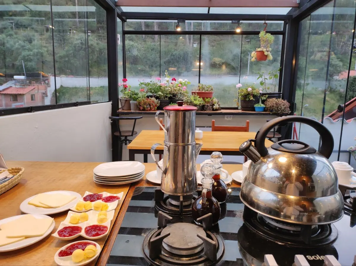 Mesa de desayuno en la terraza con tetera, frutas, queso y mermeladas